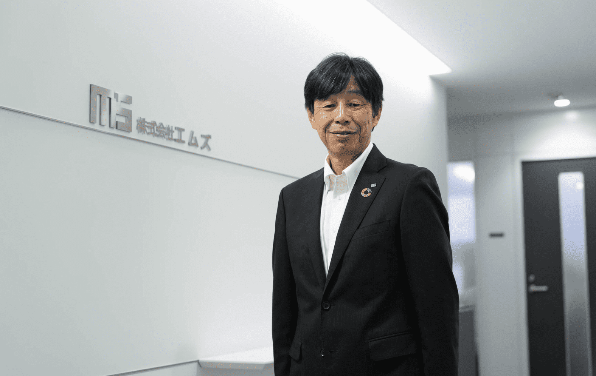 ロゴの横で微笑む代表取締役社長